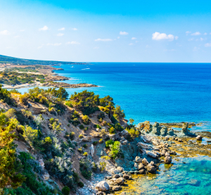 Malerische Küste Zyperns mit türkisblauem Meer, felsiger Landschaft und klarem Himmel im Frühling.