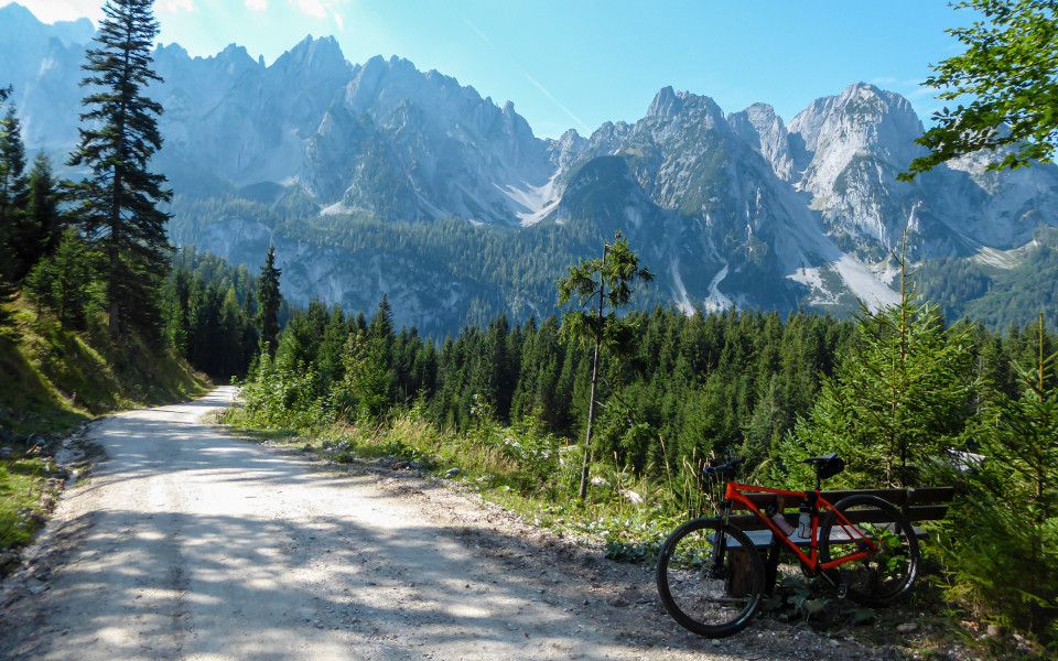 Mountainbike steht an Forststra&szlig;e im Salzkammergut mit Blick auf bewaldetes Tal und markante Kalkalpen.