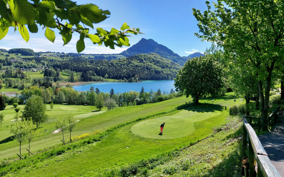 Person auf dem Golfplatz Schloss Fuschl in &Ouml;sterreich bei sonnigem Wetter mit dem Fuschlsee im Hintergrund 